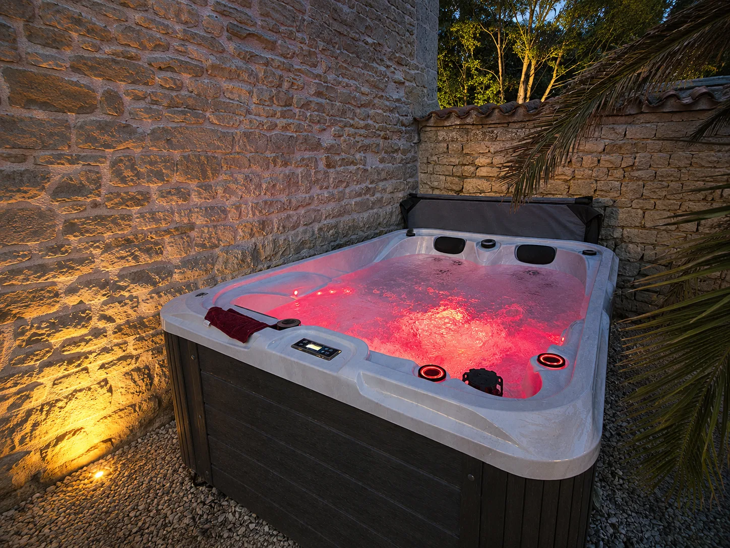 Jacuzzi extérieur en pierre avec ambiance lumineuse